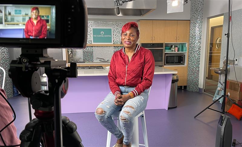 Patient Tameka Cooke sitting in kitchen on stool